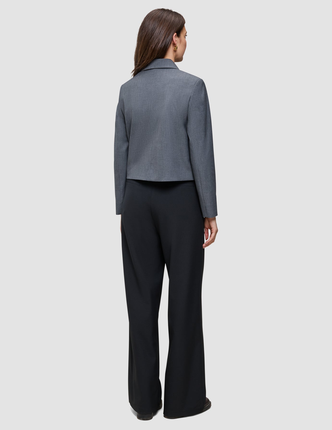 Bagfra-billede af en person iført en grå blazer og sorte Serene Pants Wide Black.